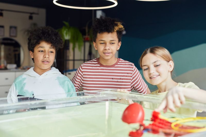 Drei Kinder bauen mit einem Roboter-Set an einem Wasserbecken